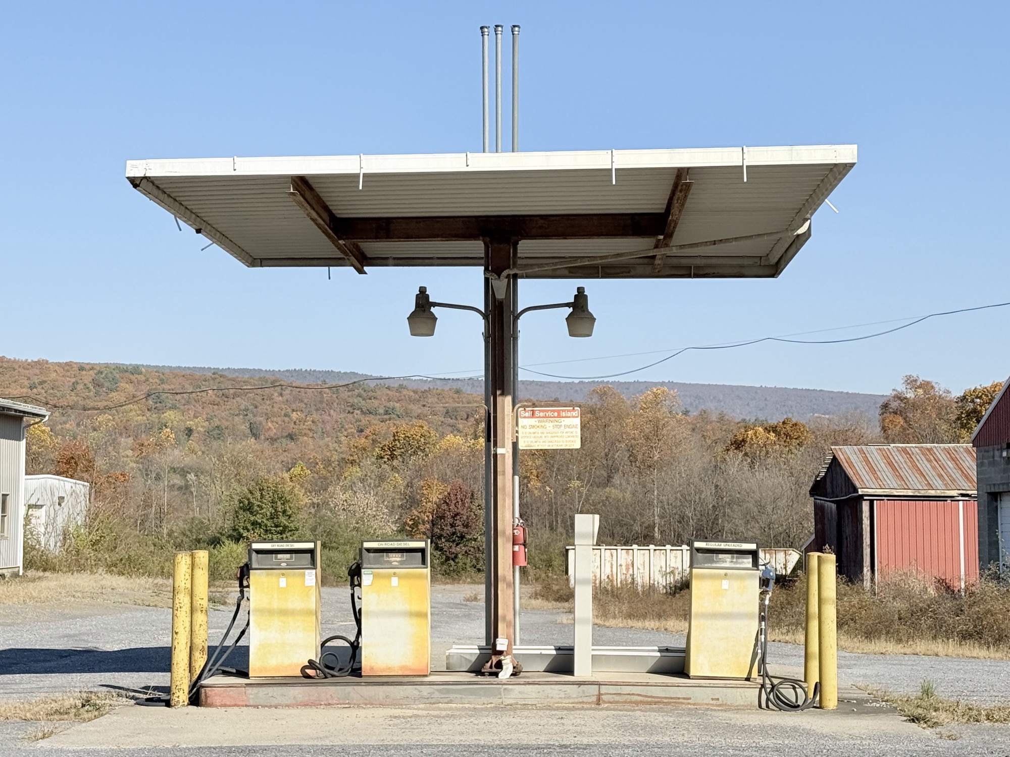 An abandoned gas station canopy against fall hills in Pennsylvania.